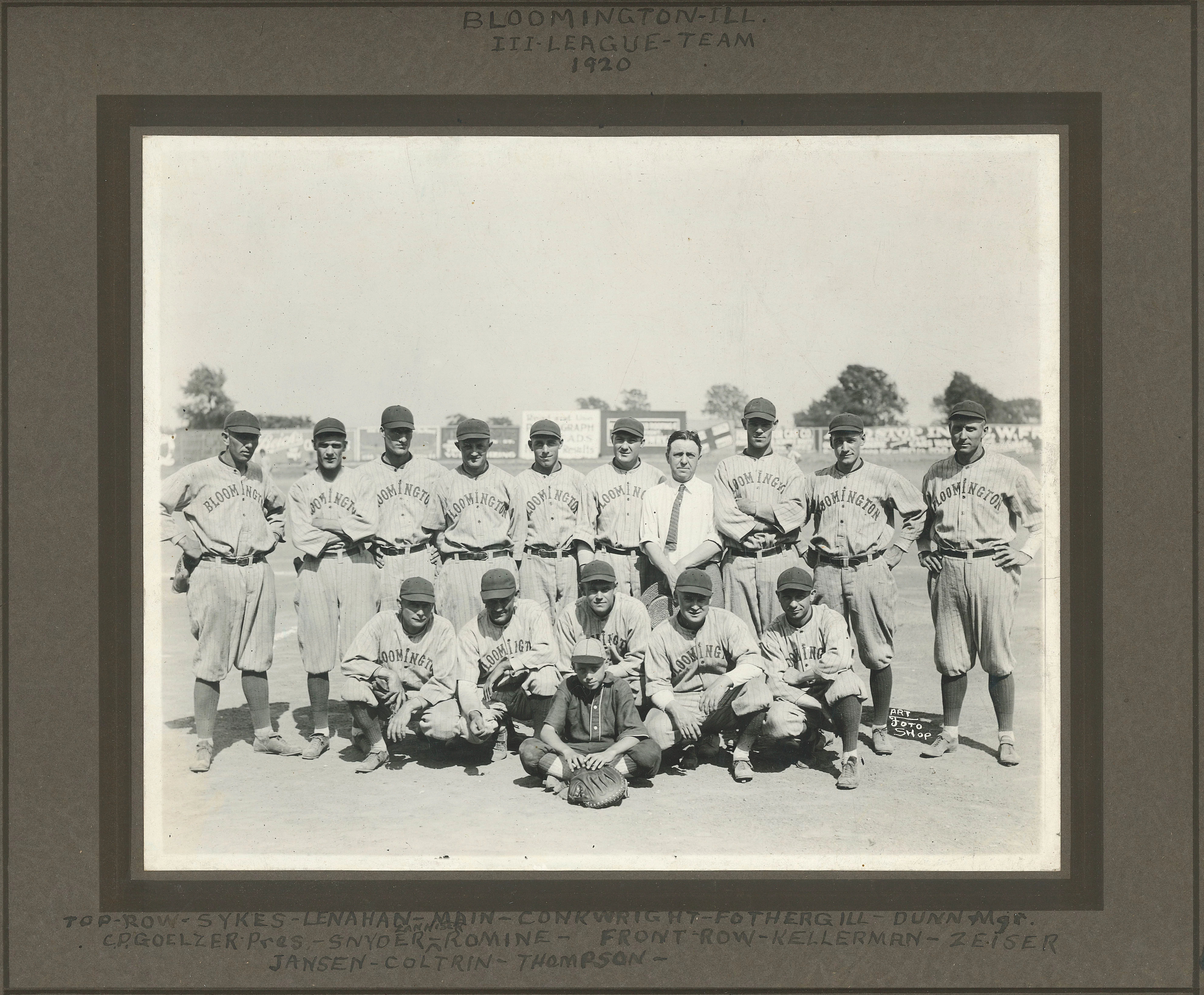 16 light-skinned men gather for a photo. All of them are in baseball uniforms and ball caps, with exception one man who is in a button-up white shirt and tie, no hat. On the border of the image each man is identified. One younger looking man in the lower center was possibly the ball-boy and not a player, he has a different uniform.