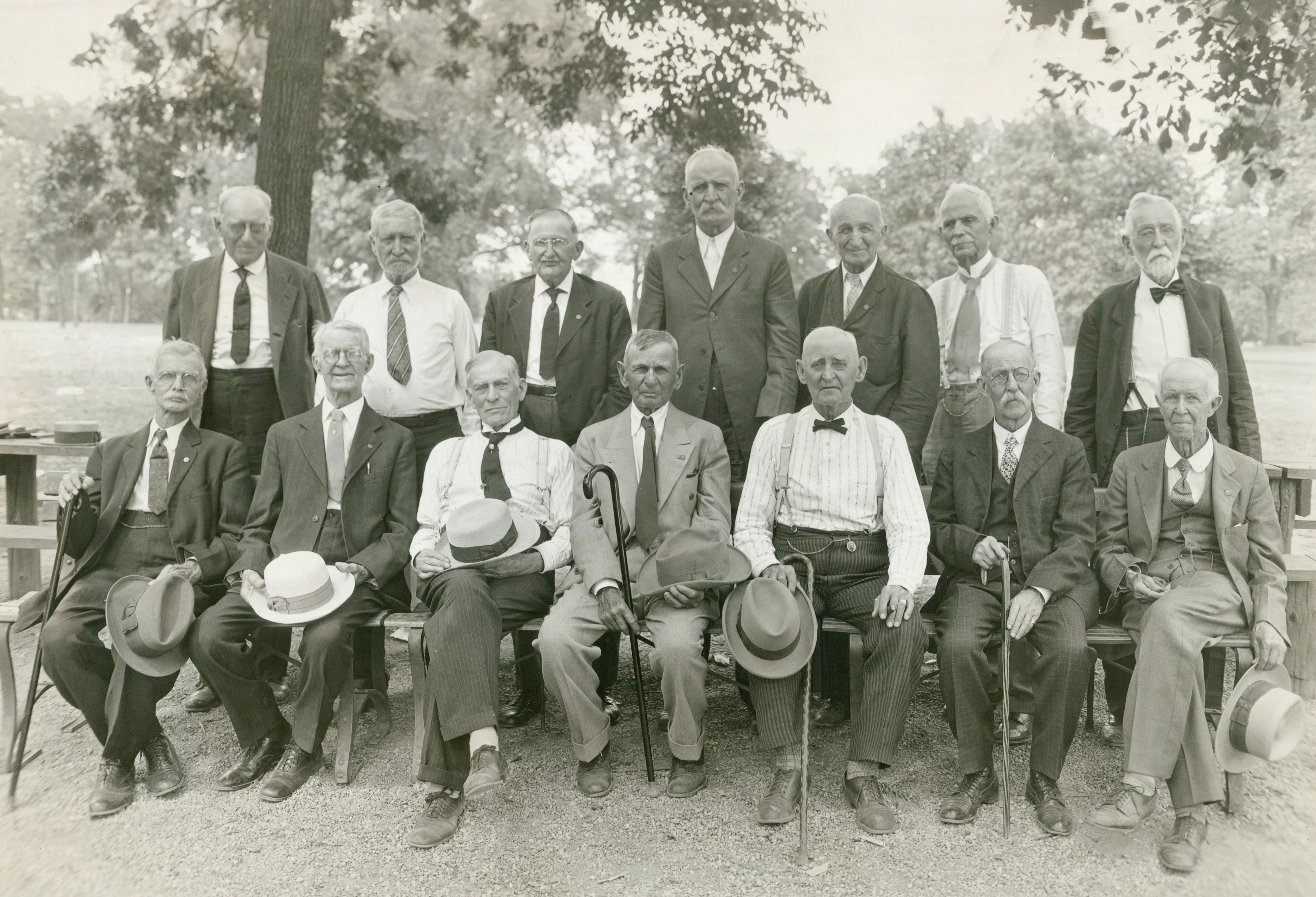 14 light-skinned men stand and sit for a photograph. They all appear to be old, some elderly.