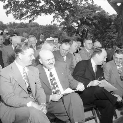 Men in suits are seated and talking and laughing.