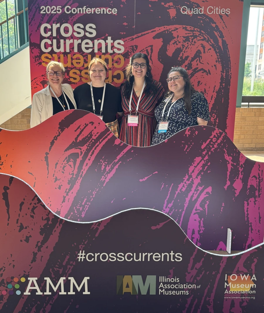 Julie, Jackie, Micaela, and Maria pose in front of a sign that reads