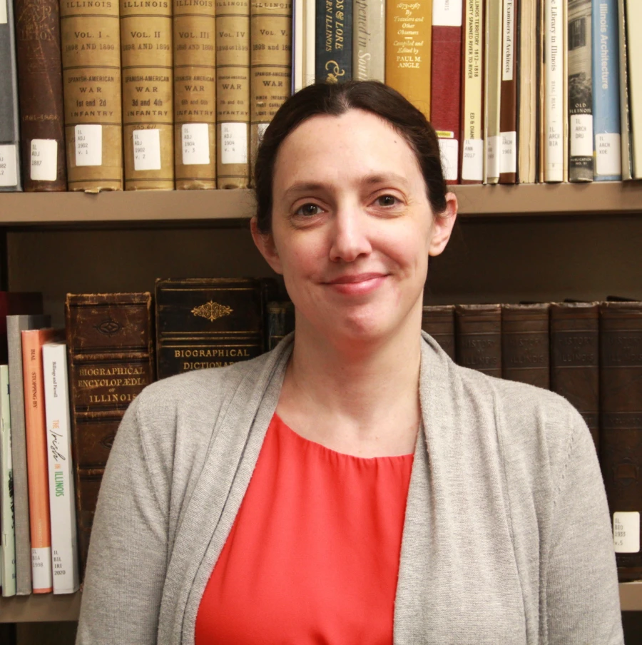Katie similes in front of books in the Library