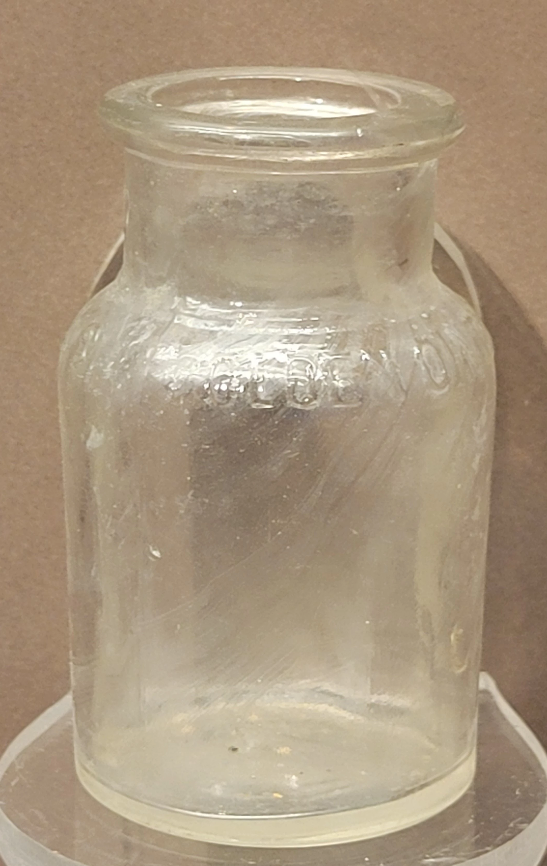 a clear glass bottle with a large opening on top. no label.