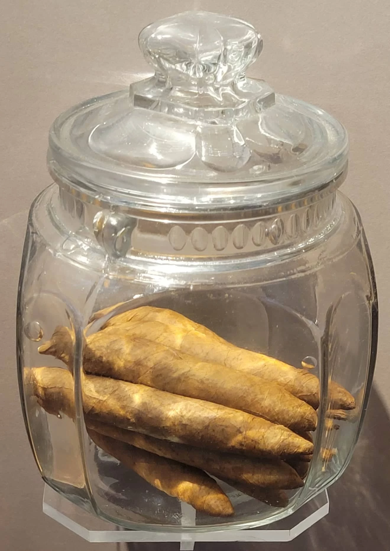Clear glass jar with lid containing eight plump, hand-rolled cigars. The cigars are medium-brown.