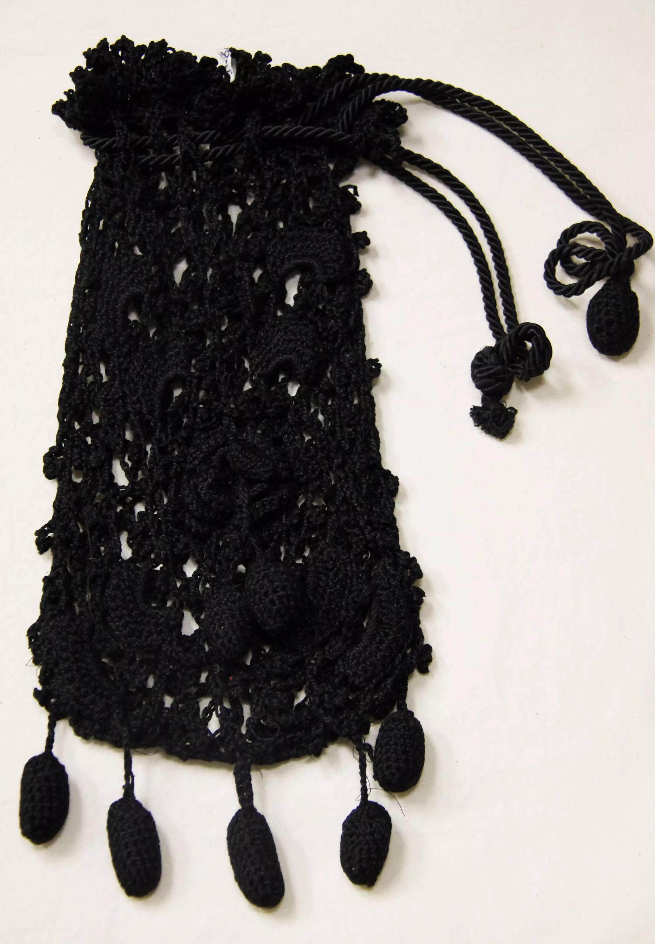Black pouch with drawstring closure. Fringe hangs from the bottom.