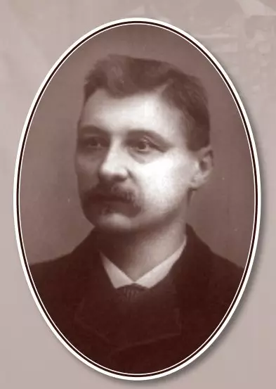Black and white portrait of a light-skinned middle-aged man with dark hair and mustache. He is wearing a white shirt, tie, and jacket.