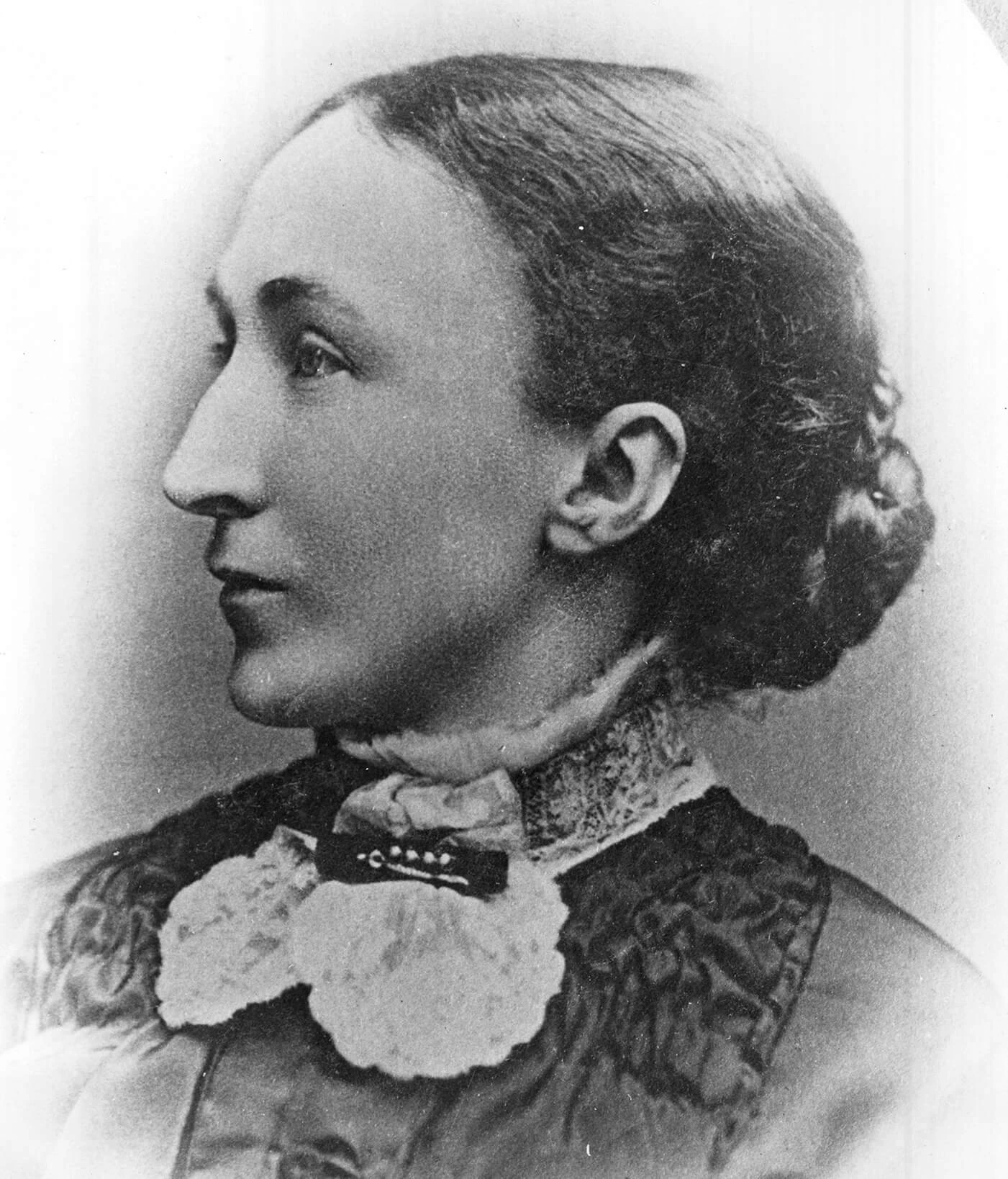 Profile portrait of Eliza Fell, a white woman wearing a high-collared ruffled dress and hair in a low bun.