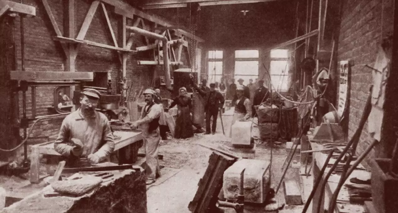 Black and white photo of several men and women working to cut and shape stone.