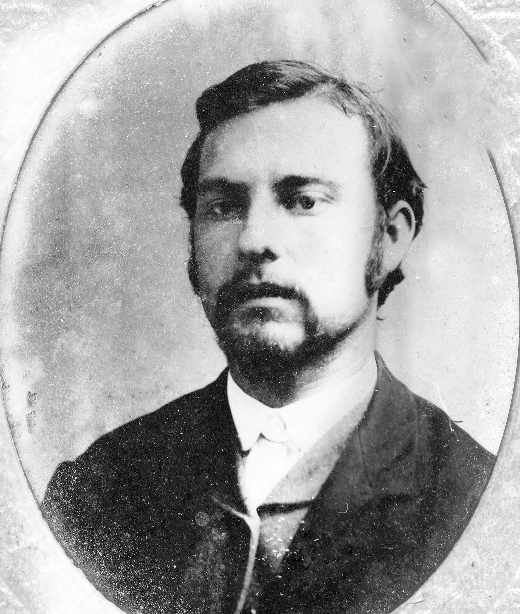 Photograph of a white man with dark hair and a goatee. He is wearing a dark suit jacket.