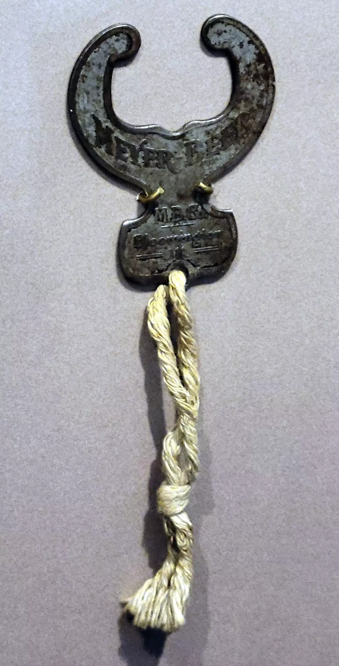 a metal bottle opener with a rope string hanging from it.
