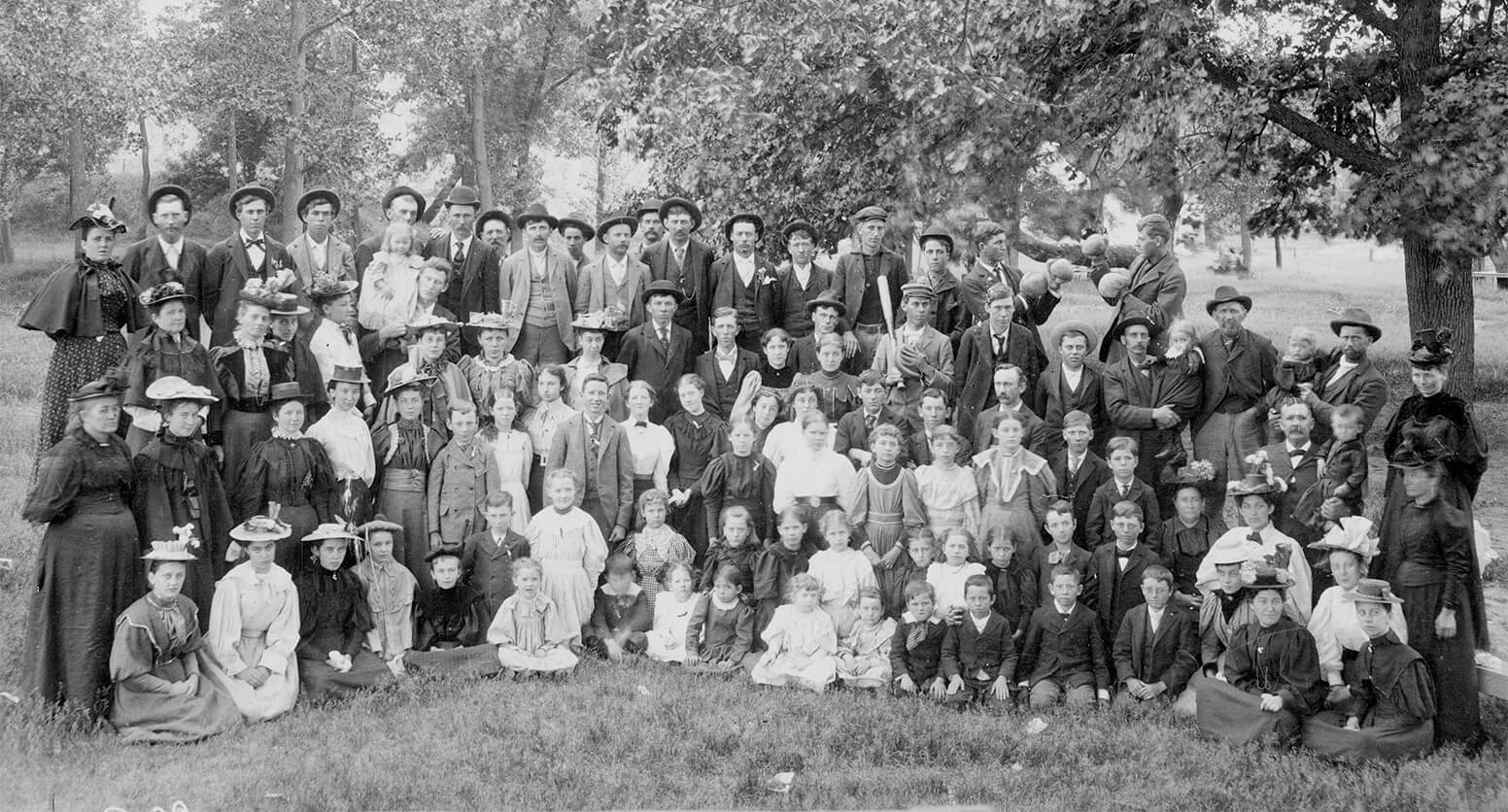 Black and white photo of a large group of men, women, and children, dressed in formal attire. There are over 50 people in the photo.