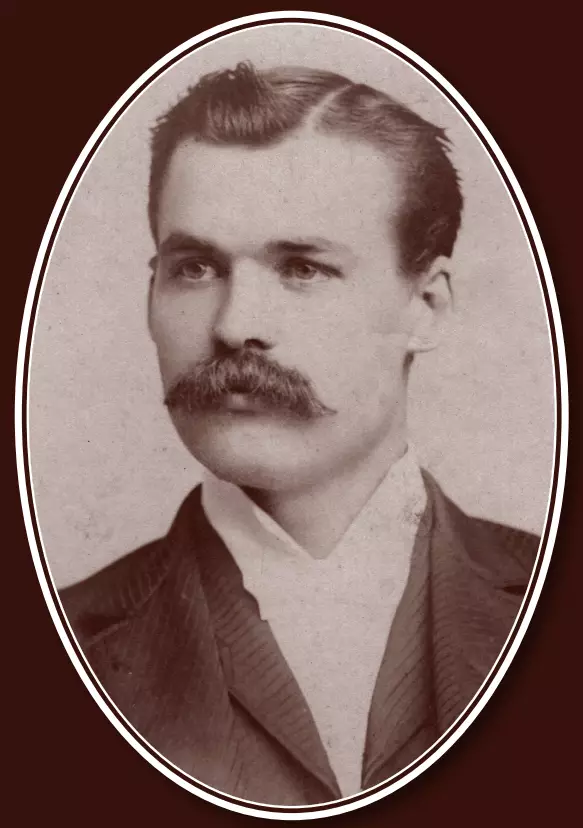 Light-skinned man with tidy combed hair and a thick dark mustache