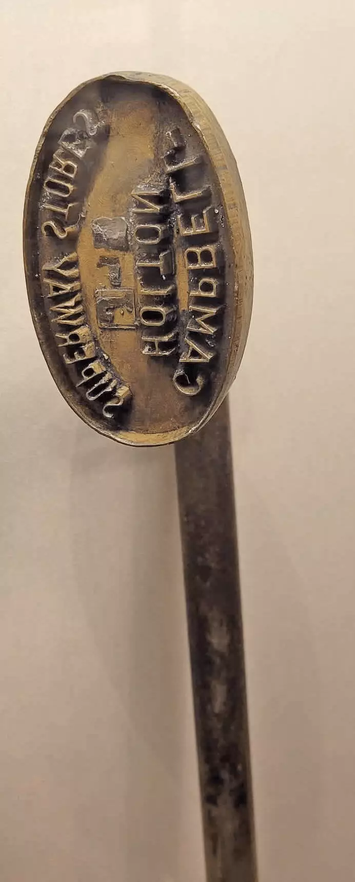 Metal stamp that has 'Campbell Holton Superway Stores' written backwards on it.