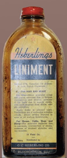 Yellowing glass bottle with red cap and a label that reads: Heberling's Liniment. For man and beast.