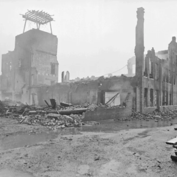 through the haze there is a crumbled brick building, some fascade still stands but most of the brick building is rubble on the ground.